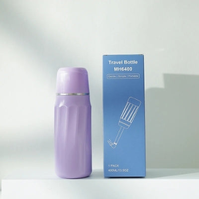 La douchette WC de couleur mauve avec sa boîte à côté d'elle.