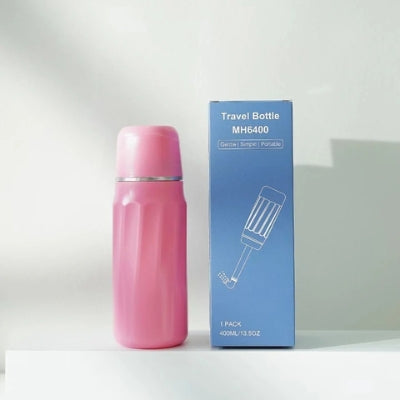 La douchette WC de couleur rose avec sa boîte à côté d'elle.