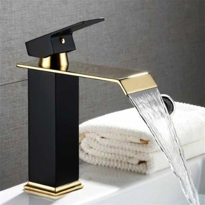 L'eau coule du robinet noir et doré directement dans le lavabo avec un bon débit sans gaspillage d'eau.