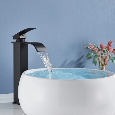 L'eau coule du robinet pour lavabo noir mat long en cascade avec un bon débit d'eau sans éclaboussures et remplit la vasque complètement.