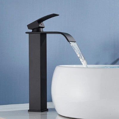 Le robinet pour lavabo noir mat long remplit d'eau la vasque ronde de couleur blanche. L'eau coule en cascade avec un bon débit d'eau.