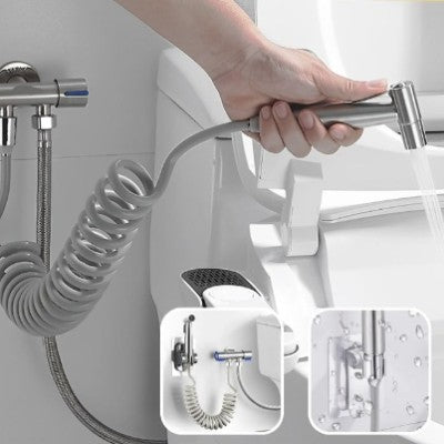 La main d'une personne actionne la douchette WC pour laver la cuvette de la toilette.
