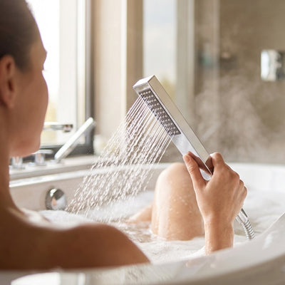 femme dans baignoire se lave avec pommeau de douche